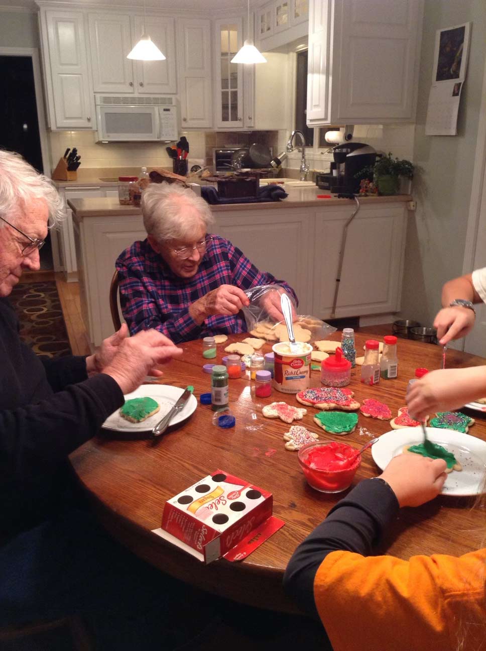 senior citizens decorating Christmas cookies at kitchen table